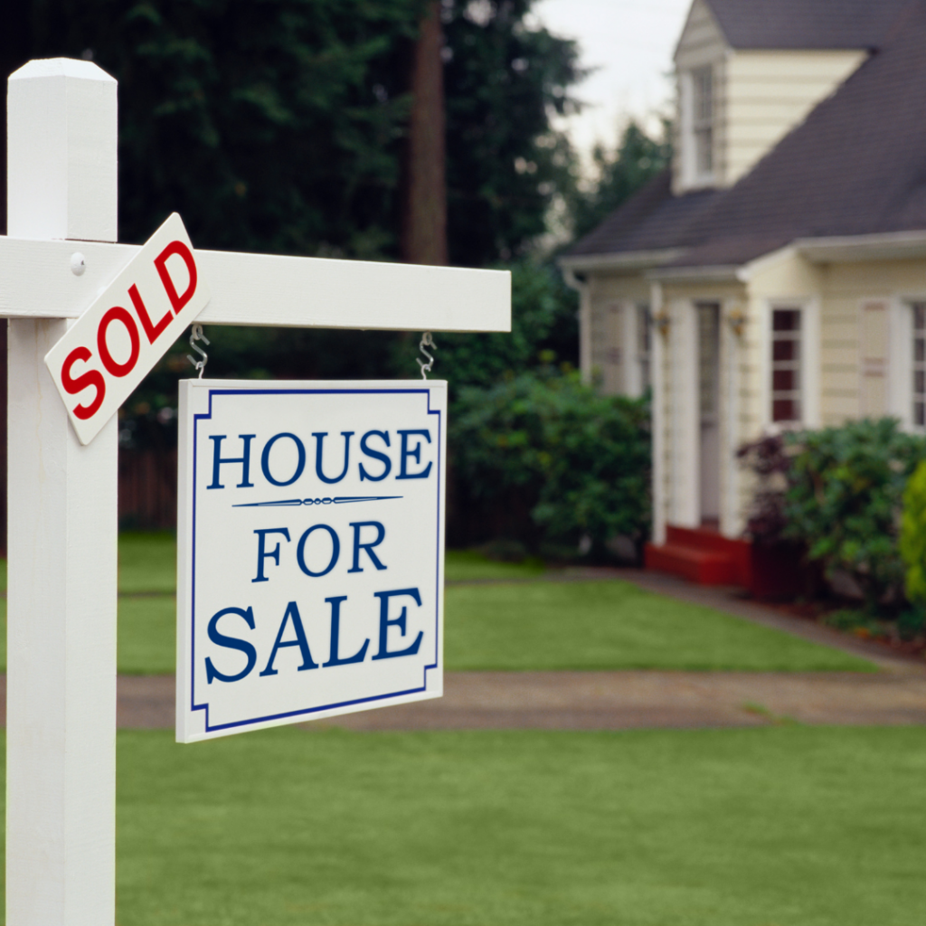 A House For Sale and SOLD sign in the front yard of a home.