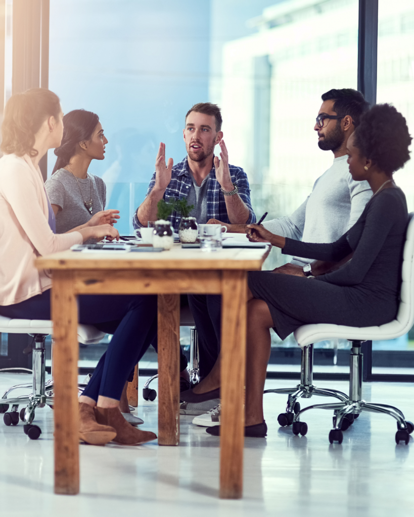Five people meeting around a table discussing business.