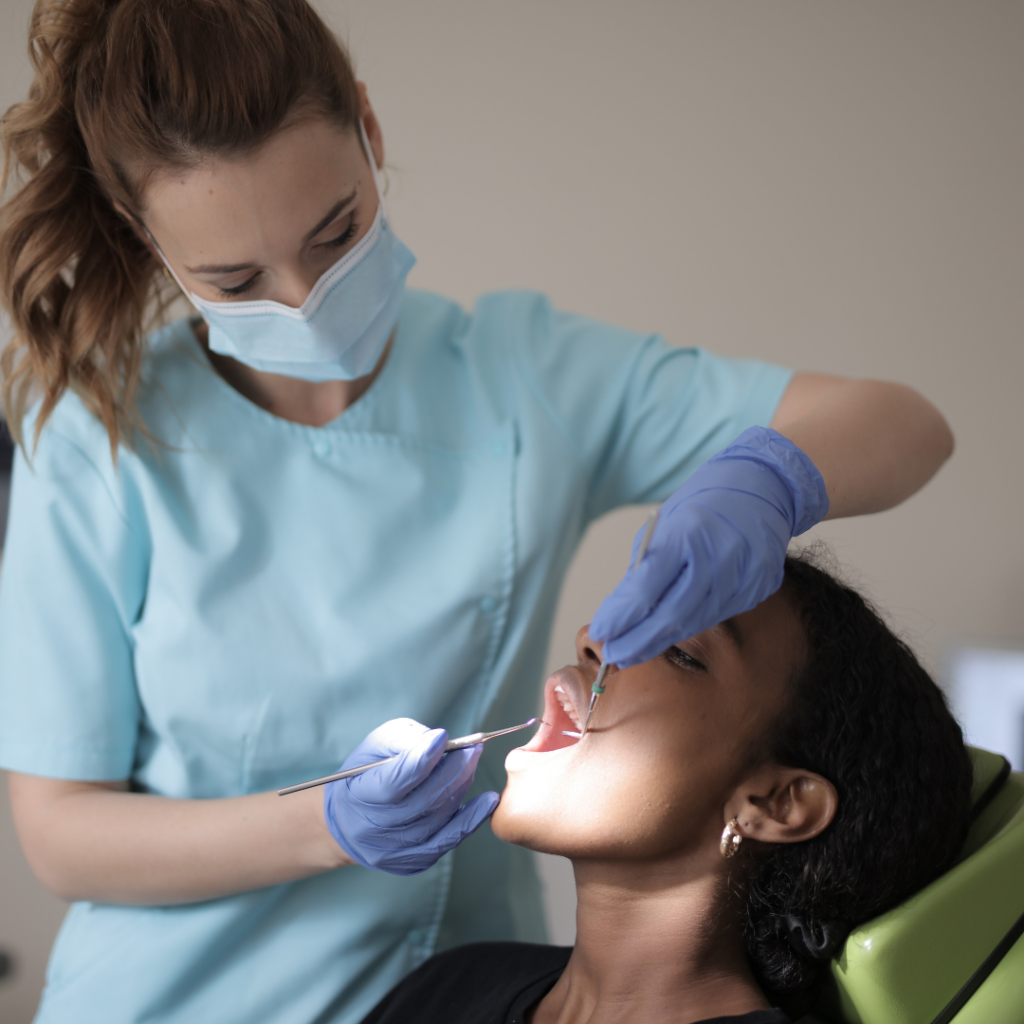 A dental hygienist examining a woman's teeth.