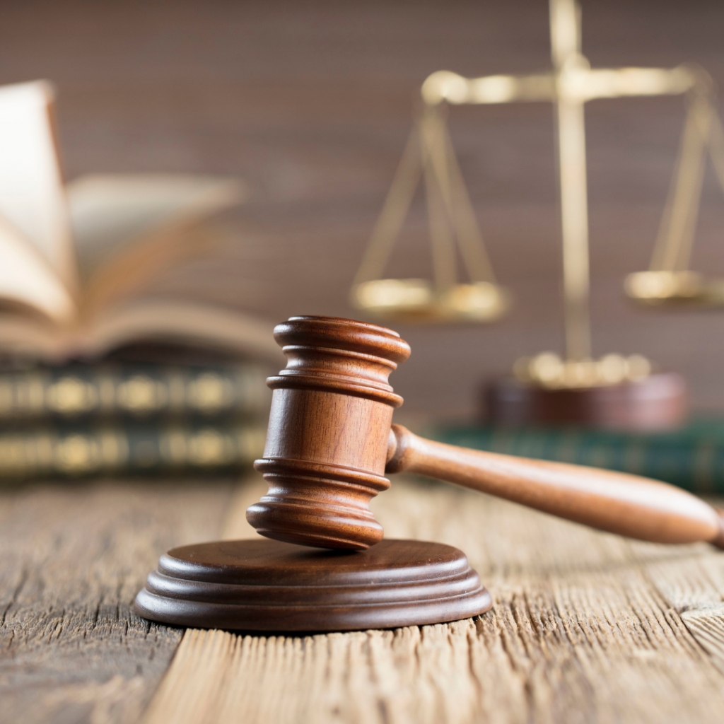 A judge's gavel in front of law books and scales of justice.